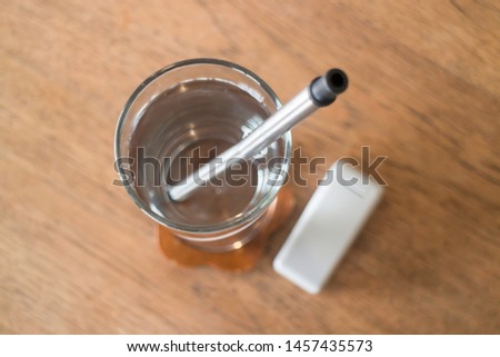 Reusable metal drinking straw in glass of water, stock photo