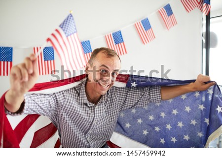 High angle portrait of balding middle-aged man waving American flag and smiling happily at camera, copy space
