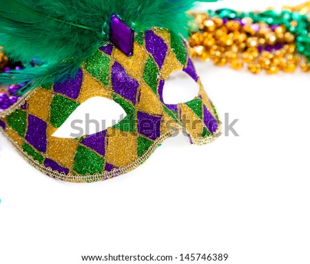A purple, gold and green mardi gras mask and beads on white