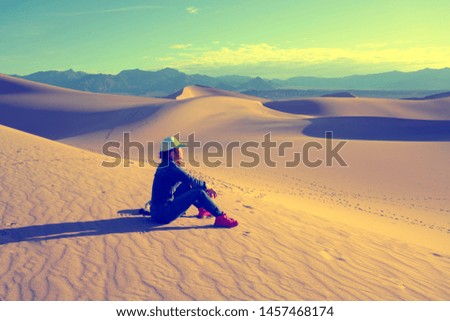 Woman sitting on Sand Dunes Desert relaxing, adventure traveling, Death Valley California, USA