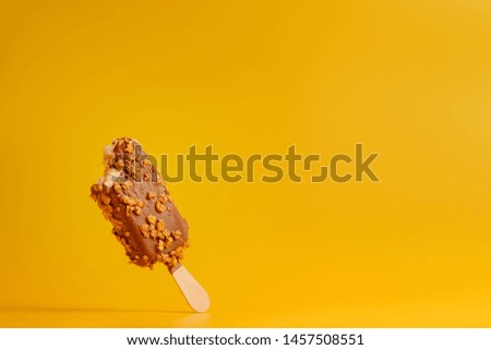 chocolate ice cream popsicle on yellow background bitten off a piece
