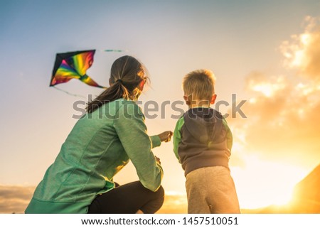 Mother and son flying a kite at sunset. 
