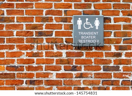 A transient boater restroom sign for Men, Women and Handicapped people written in braille also on the side of a brick building 