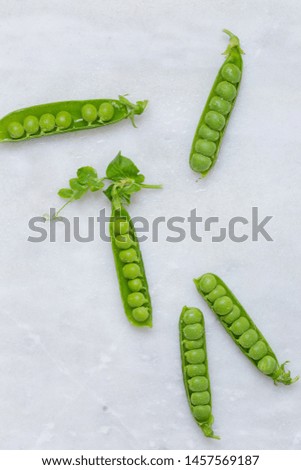 Fresh green peas in rustic plate on white marble background with copy space