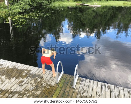 a boy jumping into the lake in a sunny day at summer. 