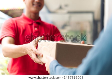 Postman delivering package of goods to home with smile and happy face. Young Asian cute girl receiving boxes from postman at the door. Selective focus on the hands. Home delivery concept. Royalty-Free Stock Photo #1457593028