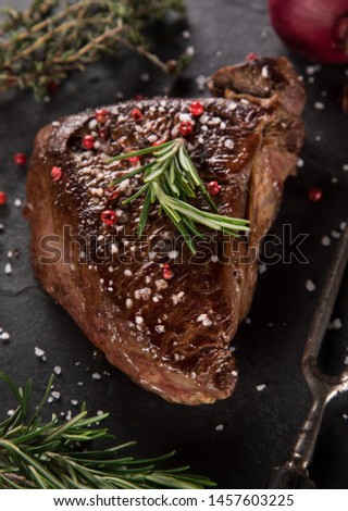 Grilled beef steak on black stone table. Top view with copy space