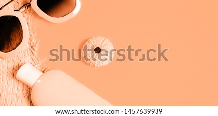 Beach accessories on a colorful background. Trendy pink sunglasses, a bottle of sunscreen lotion, a fragment of a straw hat and sea urchin shell . Summer vacation background. Top view image with copy 