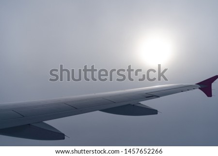 Up in the air, view of aircraft wing silhouette with dark blue sky horizon and cloud background in sun rise time, viewed from airplane window Royalty-Free Stock Photo #1457652266