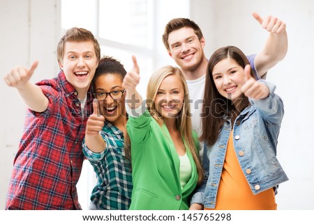 education concept - happy team of students showing thumbs up at school Royalty-Free Stock Photo #145765298