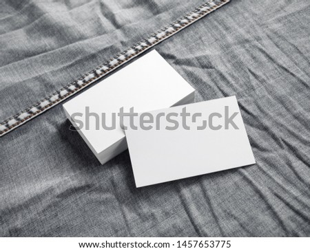 Blank white business cards on gray denim background.