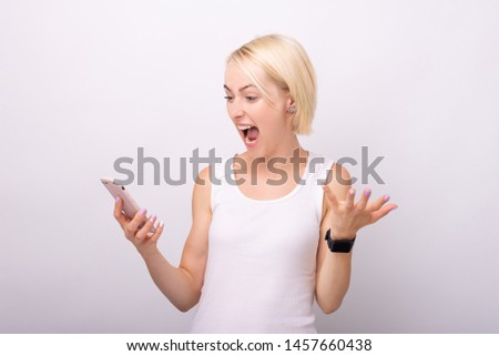 Photo  of a very excited young woman, screaming and holding a smartphone over isolated background  