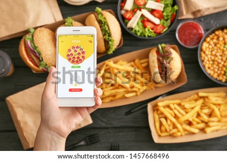 Woman with mobile phone ordering food online Royalty-Free Stock Photo #1457668496