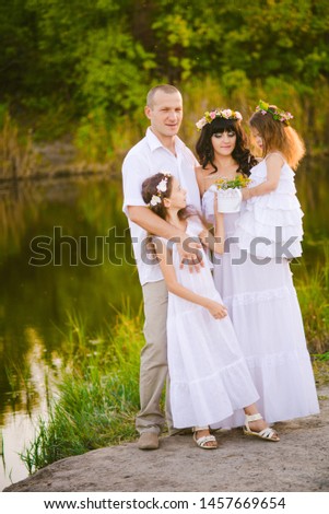 Happy parents and children having fun outdoors in a wheat field and river summer at sunset