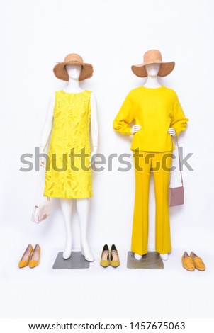 Female yellow clothing with sundress and yellow trousers ,straw hat, handbag on two mannequin isolated
