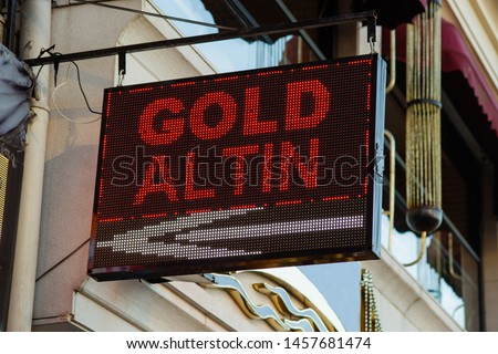 Red colored Gold text written on a black background led board hanged on the wall in a street. Word Altin means gold in Turkish language.