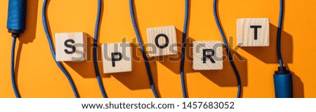 panoramic shot of jumping rope near wooden cubes with sport lettering on yellow 