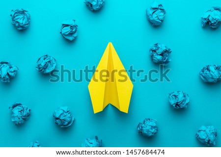 Great business idea concept with blue crumpled office paper and yellow paper plane in the centre. Top view of brainstorming concept over turquoise blue background. Creative idea concept background. Royalty-Free Stock Photo #1457684474