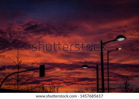 Reddish sky behind the silhouettes of lampposts and traffic lights