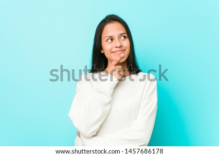 Young pretty hispanic woman looking sideways with doubtful and skeptical expression.