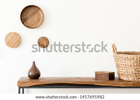 Design scandinavian interior of living room with wooden console, rings on the wall, vase, rattan basket and elegant accessories. Stylish composition of home interior. Home decor. Template. Copy space.