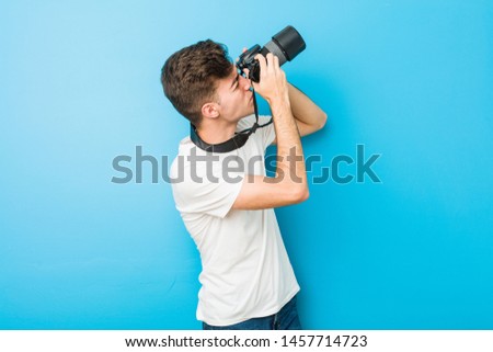 Teenager caucasian man taking photos with a reflex camera