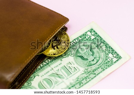 Bitcoin and leather wallet with one dollar bill isolated on pink background.