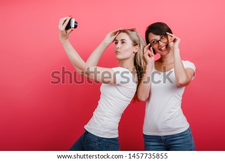 Two women friends posing in the studio - take a selfie picture, funny time. Emotion concept