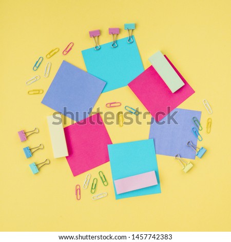 Multicolored sticky notes and paper clip on yellow surface