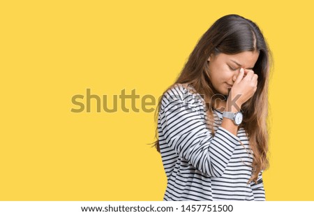 Young beautiful brunette woman wearing stripes sweater over isolated background tired rubbing nose and eyes feeling fatigue and headache. Stress and frustration concept.