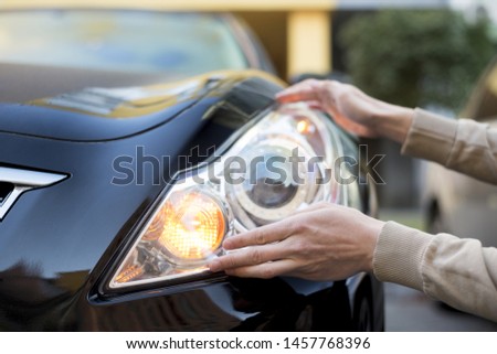 Hand holding headlight of darkÂ car