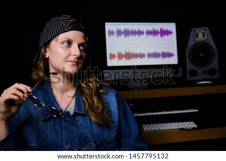 Young woman singer, a portrait in a recording Studio. Girls with glasses in their hands to record music in the Studio. The musician sits in the place of the sound engineer next to the monitor.