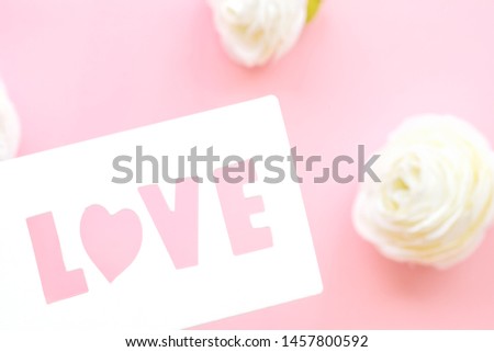 White gift tag with inscription love, on a pink background, adorned with delicate white roses.