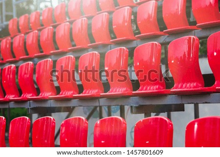 Rows of empty plastic red seats at a small stadium. Outdoors, sunny day. Concert, sports, show concept. Selective focus image