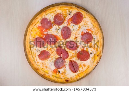 Salami pizza on wooden board on the table. Close-up top view