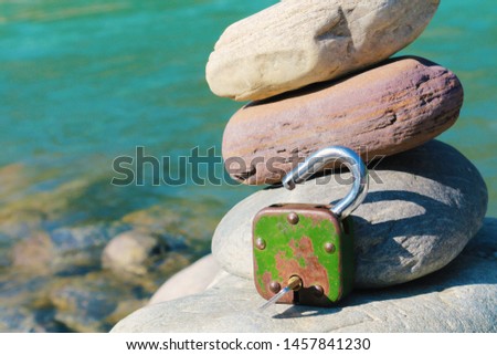 Old padlock open key. The key sticks out in the lock. The lock lies on a stone. Conceptual photo - the answer or the solution of something.