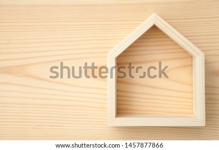 Simple wooden frame in shape of  house on wooden background . Symbol for new home construction. 