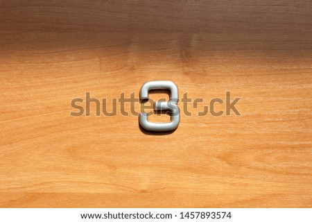 Table number three hanging on a wooden door. Concept of a hotel room home or office. Copyspace