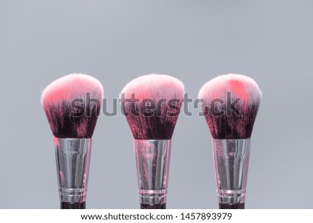 Powder brushes on light background with pink powder splash close up