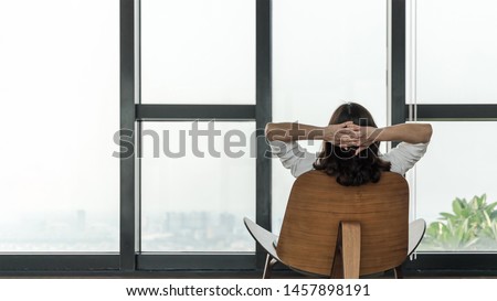 Condo living lifestyle, luxury condominium home life style of happy working woman take it easy relaxing, resting on comfort chair in building tower or city hotel lobby interior with rooftop view Royalty-Free Stock Photo #1457898191