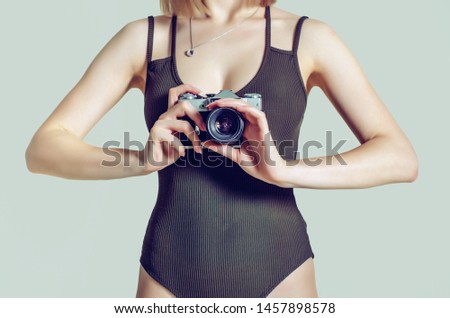 girl holds a vintage camera in her hands on the chest level