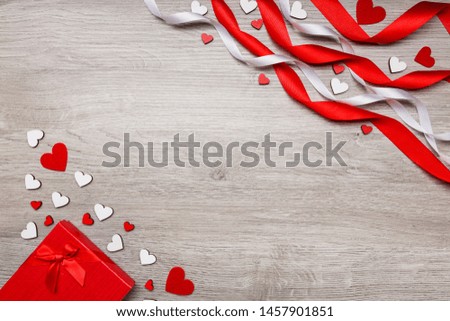 Love and holiday greeting concept background. Symbol of love. Heart decor. Place for text. Red gift box. Red and white ribbons and wooden heart.