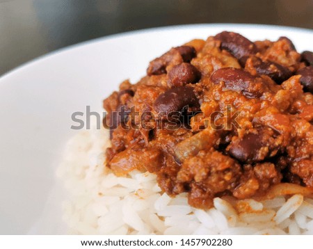 Chilli con carne with rice on a white plate. Traditional Mexican food.