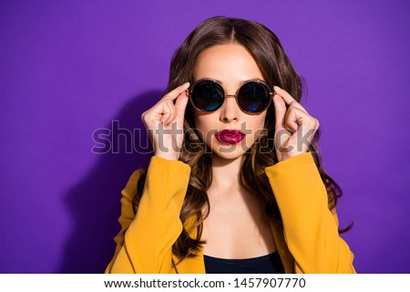 Photo of cool astonishing girl watching into camera through sunglass while being isolated with purple background