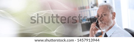 Senior businessman talking on mobile phone in office; panoramic banner
