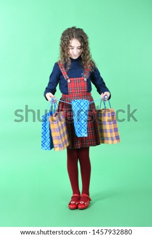 Child with a packaging checkered texture isolated on white background. Girl likes shopping on sale season. Holiday present, shopping. High resolution photo. Full depth of field.