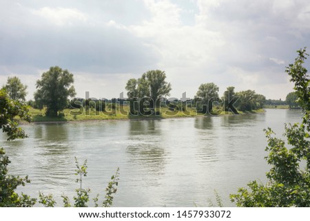 View on the river IJssel in the province of Gelderland in the Netherlands. The IJssel is a beautiful old river meandering through the lowlands with beautiful trees and rural environment at the shores. Royalty-Free Stock Photo #1457933072