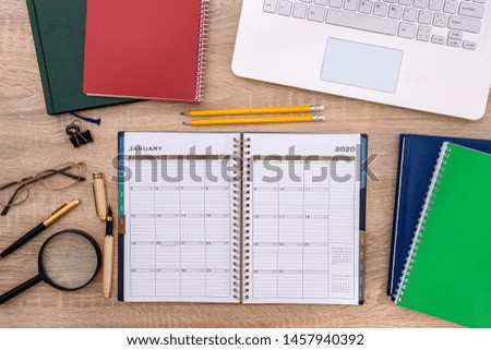 Opened notepad with laptop on wooden table