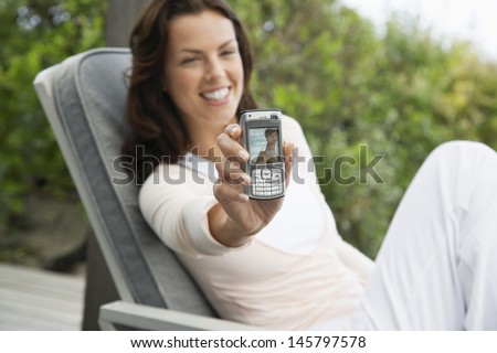Smiling young woman holding up picture message on porch
