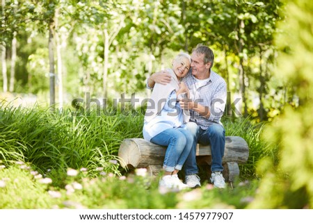 Full length portrait of loving senior couple embracing playfully while enjoying date in Summer park, copy space